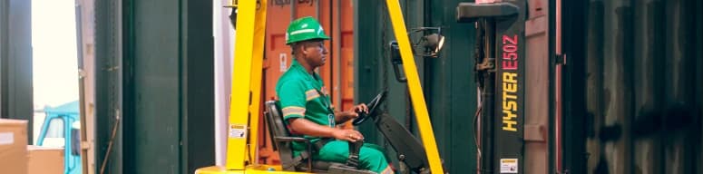 Profissional com equipamentos de proteção individual em operação de movimentação de contêineres